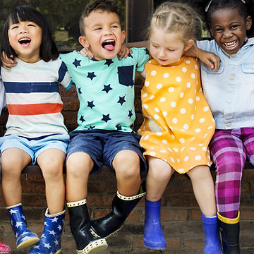 A group of children sitting on a bench
Description automatically generated